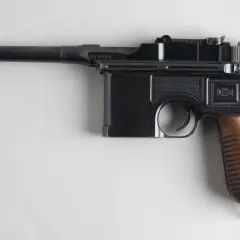 Czarny pistolet Mauser C96 z drewnianą rękojeścią, często uważany za pierwszy pistolet na świecie.