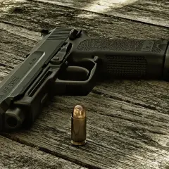Pistolet HK USP EXPERT kaliber .45 Auto i nabój na drewnianym stole.