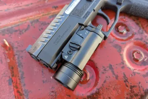 Pistolet CZ z zamontowaną latarką taktyczną, gotowy do akcji. Ta **braun broń** to solidne narzędzie.
