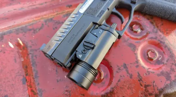 Pistolet CZ z zamontowaną latarką taktyczną, gotowy do akcji. Ta **braun broń** to solidne narzędzie.