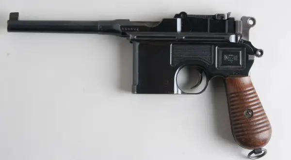 Czarny pistolet Mauser C96 z drewnianą rękojeścią, często uważany za pierwszy pistolet na świecie.