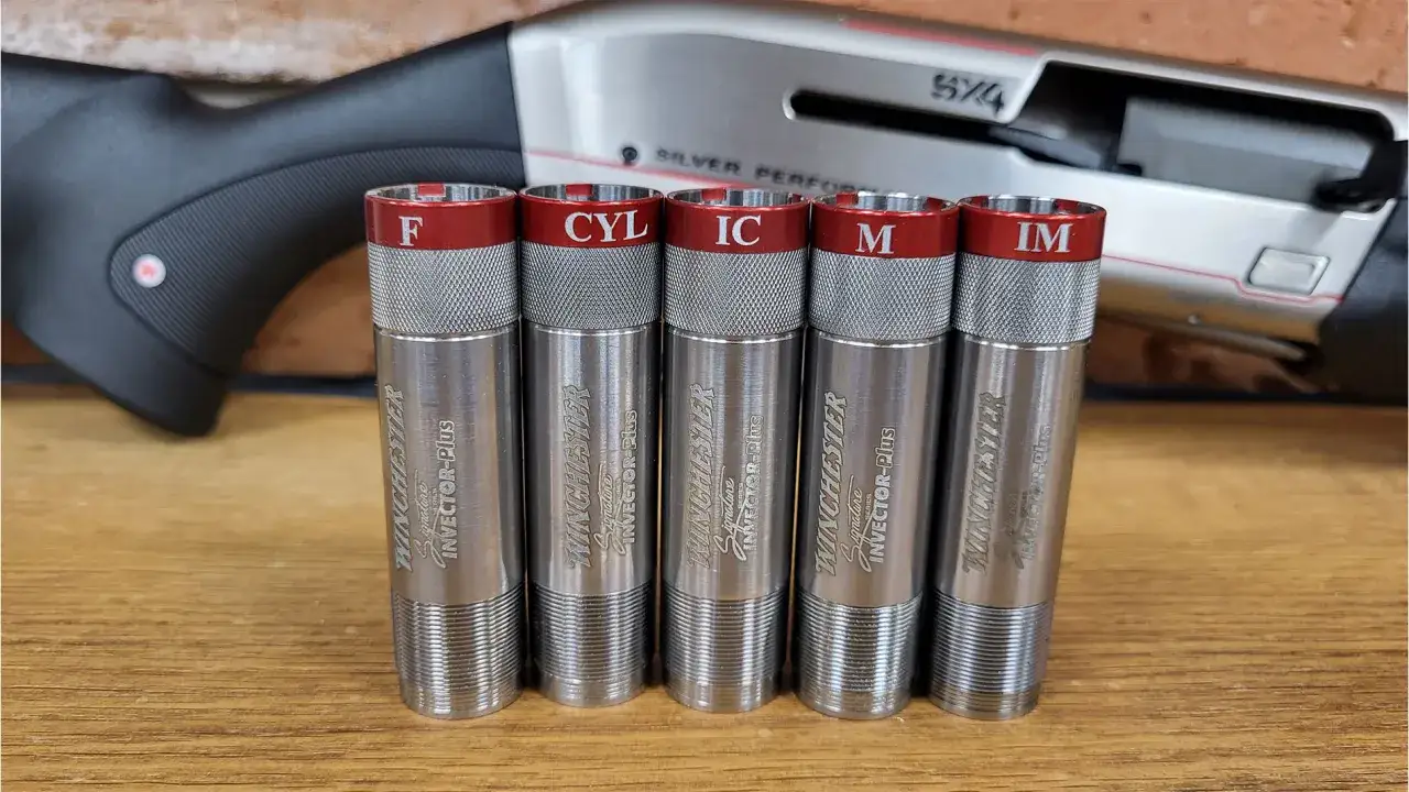 Pięć czoki oznaczenia: F, CYL, IC, M, IM, leżących przed strzelbą Winchester.
