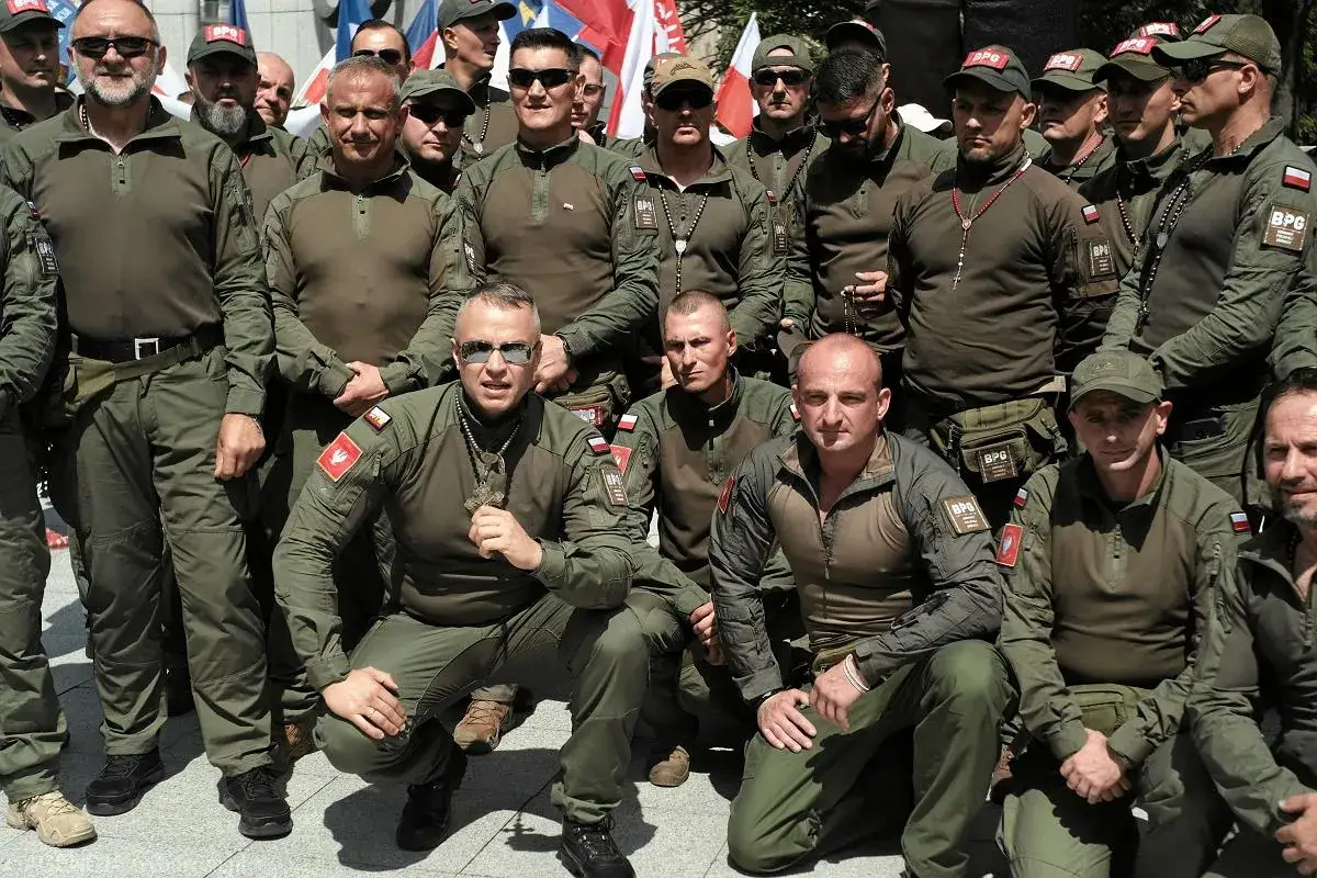 Grupa mężczyzn w mundurach, niektórzy z naszywkami BPG. Jeden z nich trzyma duży, brązowy broń.