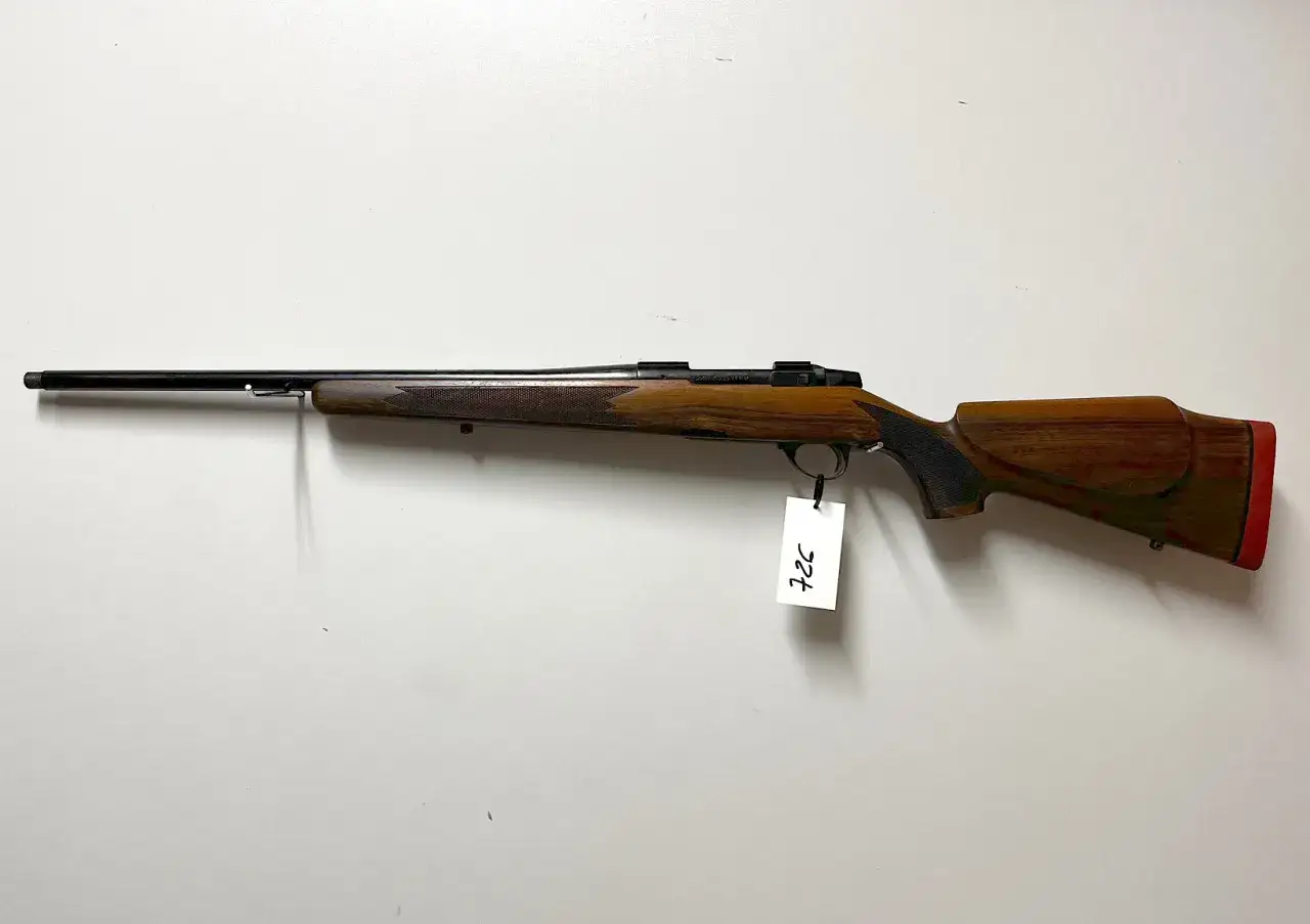 Elegancki karabin myśliwski, kaliber 243 win, z drewnianą osadą i czerwonym stopką.