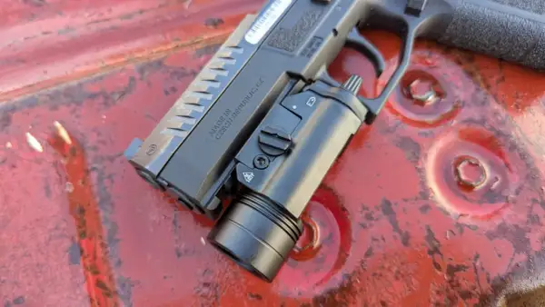 Pistolet CZ z zamontowaną latarką taktyczną, gotowy do akcji. Ta **braun broń** to solidne narzędzie.